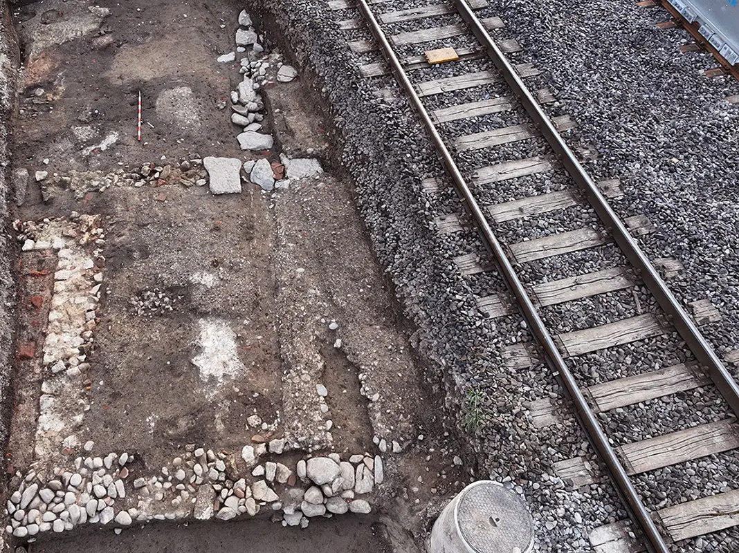 Sous un ancien quai démonté, la façade nord de la domus révèle une enfilade de pièces aux sols en béton
