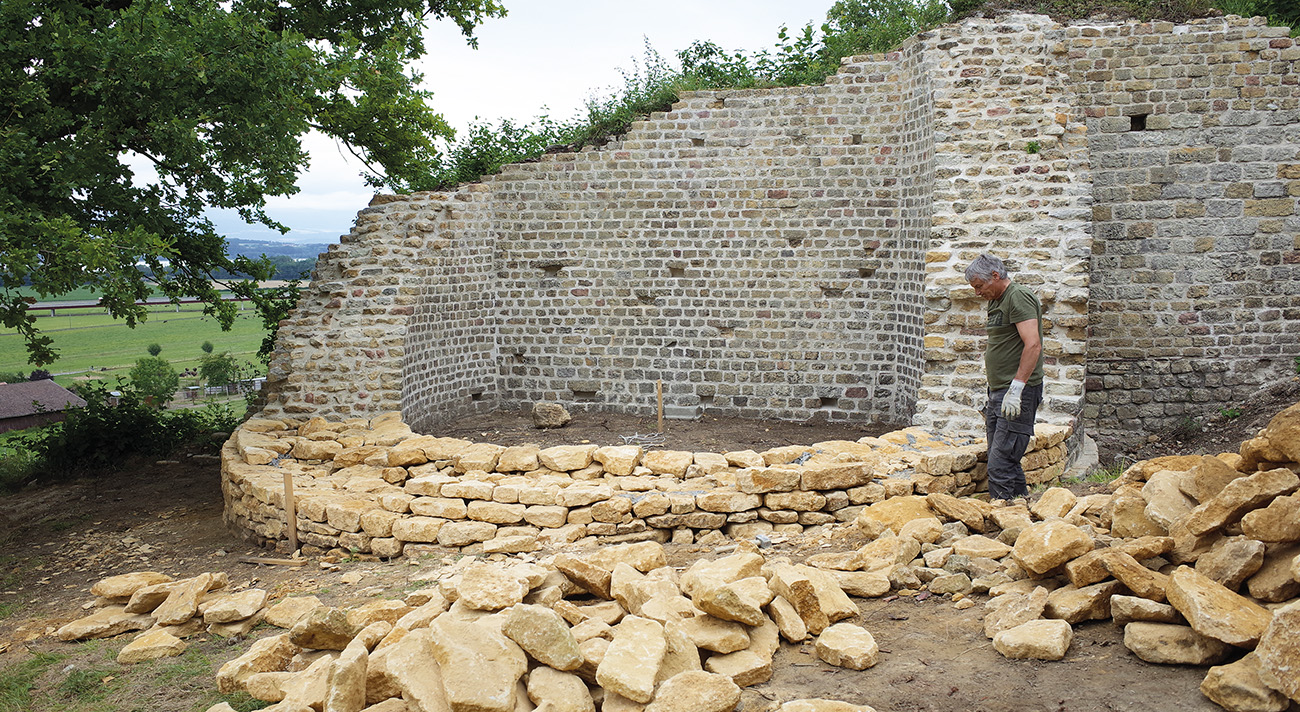 Un conservateur-restaurateur sélectionne des blocs de calcaire, devant le mur antique