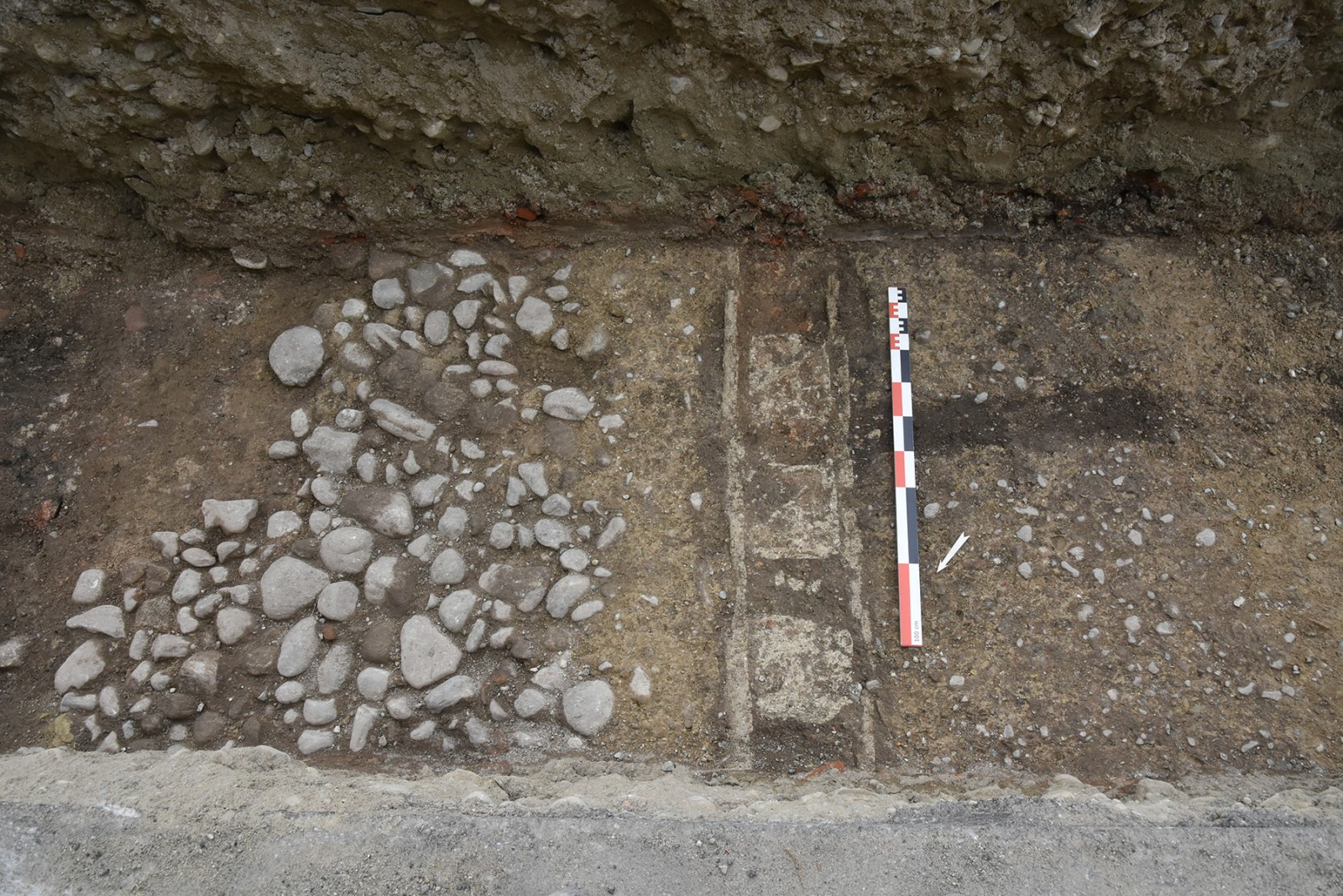 Soubassement d'une paroi en terre et bois avec négatif de poutre verticale et enduit de mortier de chaux