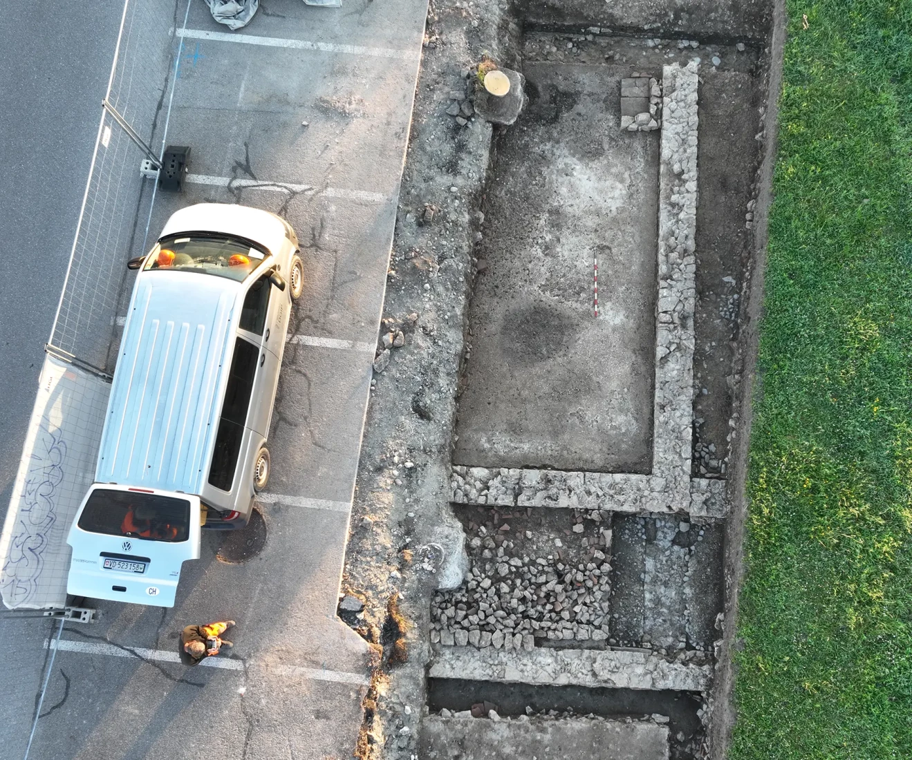 Grande pièce dotée d'un sol en béton avec un foyer (en haut) et bordée d'un couloir (en bas)