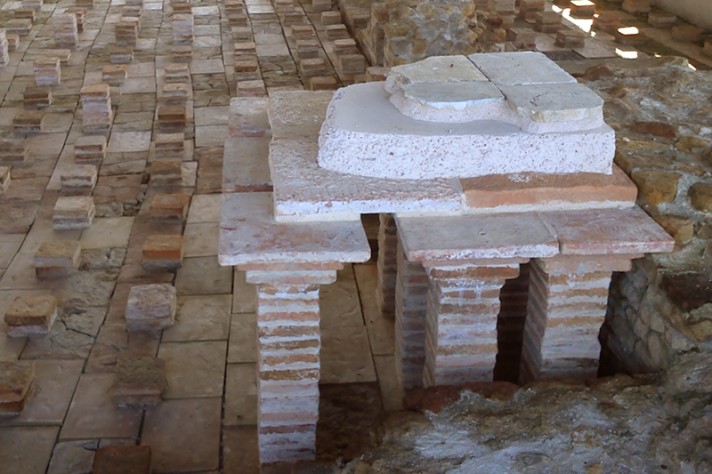 Restitution du dispositif de chauffage par le sol: les piles en carreaux de terre cuite supportaient un épais sol constitué de plusieurs couches (dalles en terre cuite; mortier hydraulique; revêtement de surface en marbre)