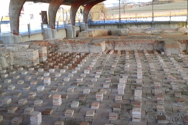 Vestiges restaurés des piles de carreaux de terre cuite appartenant au dispositif de chauffage par le sol du tepidarium. Au second plan, le frigidarium