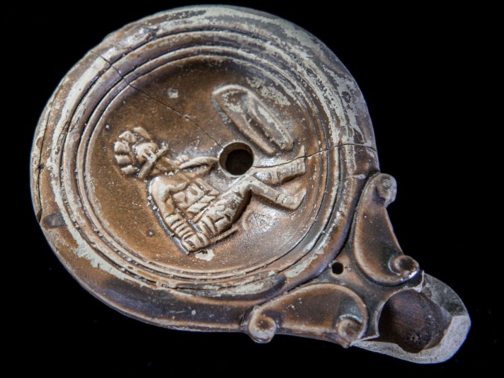 Lampe à huile en terre cuite représentant un gladiateur assis © Site et Musée romains d'Avenches, photo NVP3D
